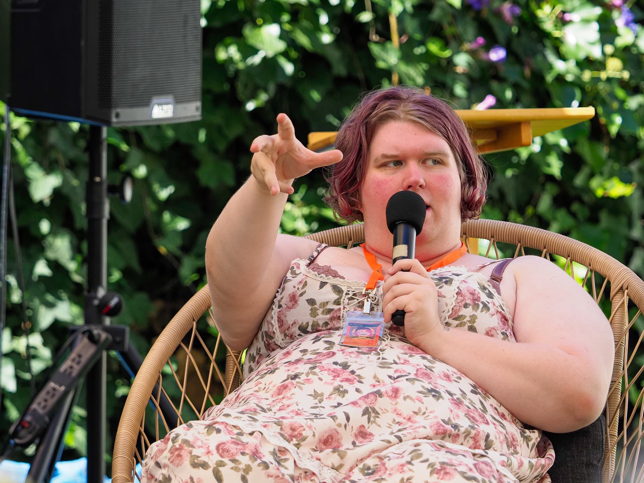 Jay Dragon speaking into a microphone on an outdoor panel at Metagame 2025
